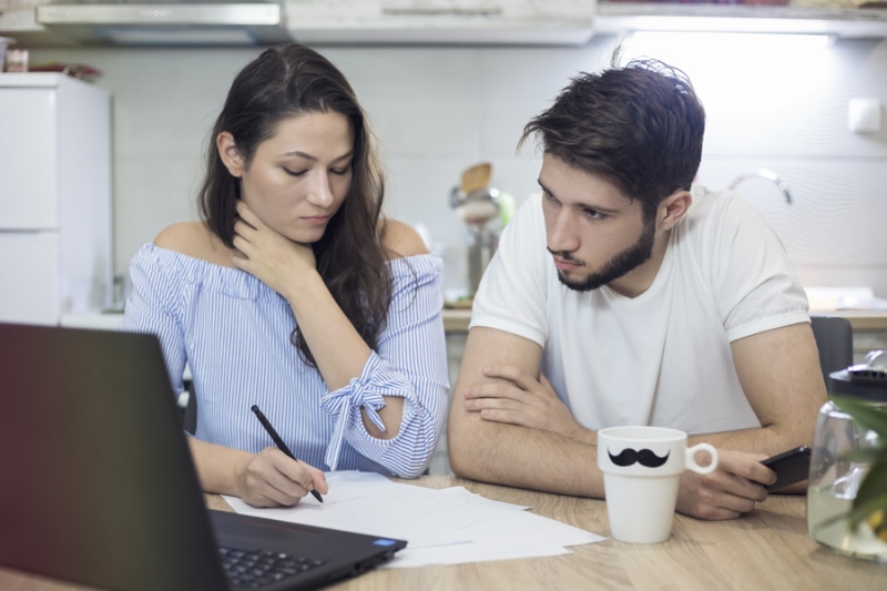 Couple researching if they should get air conditioning repair or replacement service. Millenium Mechanical Services blog image.